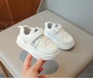 Gros plan de baskets blanches en cuir pour enfants avec scratchs et logos de sport