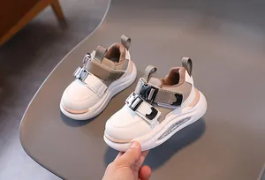 Detail of kids leather sneakers showing metal buckle strap and thick cushioned sole