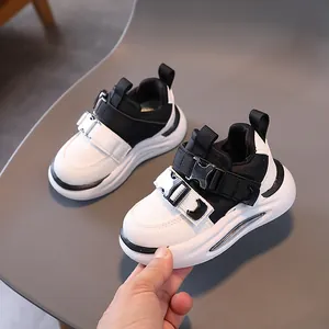Kids black and white leather sneakers with buckle straps and thick cushioned soles