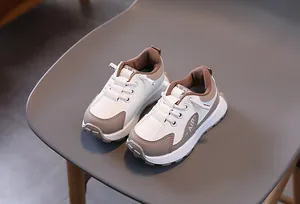 Détail de baskets enfant avec panneaux en cuir marron et blanc et logo AIP imprimé