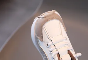 Détail de baskets pour enfants blanches et beige montrant le logo AIR et textures