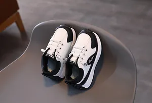 Détail de baskets pour enfants avec empiècements en cuir noir et blanc et lacets élastiques