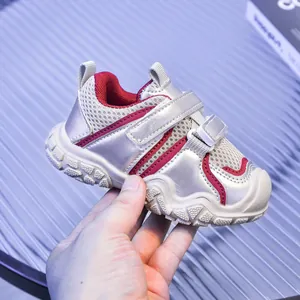 Detalle de zapatillas plateadas para bebé con ribete rojo y doble cierre de velcro ajustable