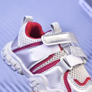 Vista macro de zapatillas infantiles de malla con cuero plateado y detalles rojos