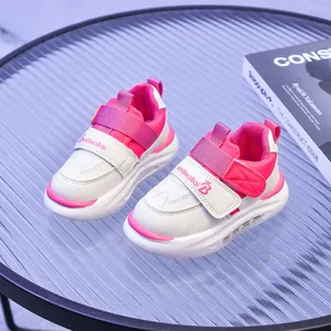Dettaglio di scarpe sportive per bambini rosa e bianche con velcro su tavolo strutturato