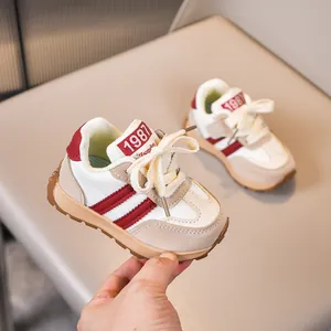 Details von Kinder-Sportschuhen mit beigem Mesh, roten Streifen und 1987-Tag auf der Zunge