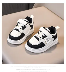 Detail of kids black and white sneakers with velcro closure and thick white soles