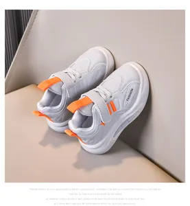 Detail of kids athletic shoe with leather upper, velcro strap and orange accents