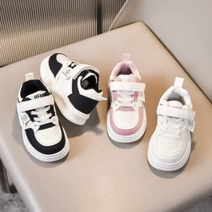 Close-up of children's faux leather sneakers in black, pink, and white with velcro straps