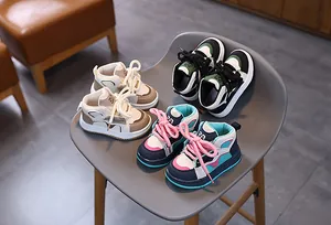 Detailansicht von drei Retro-Kinder-Sneakern in verschiedenen Farben auf einem Stuhl
