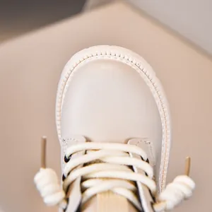 Close-up of children's cream leather boots showing round toe and white woven laces