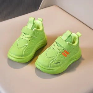 Detail of neon green kids sneakers featuring orange stripes and Velcro strap closure