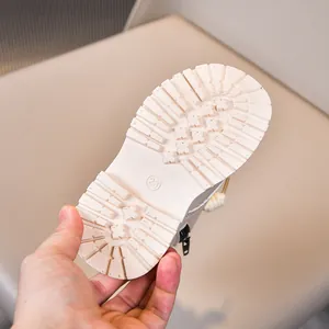 Detail view of anti-slip thick rubber sole with cross pattern on kids beige boots