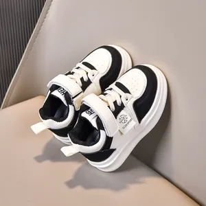 Detail of kids black and white sneakers showing faux leather texture and velcro strap
