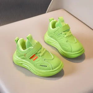Detail of neon green kids sneakers featuring orange stripes and velcro closure