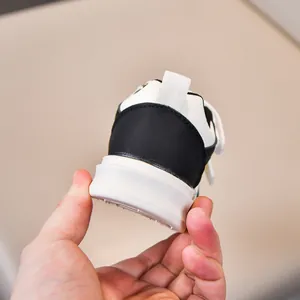 Detailed close-up of kids' black and white sneakers featuring thick soles and heel pull tabs