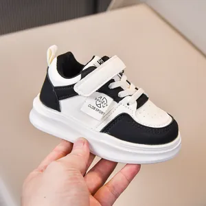 Detail view of children's black and white leather sneakers with velcro strap and logo label