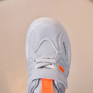 Detail of grey mesh kids sneaker showing orange straps and FASHION logo text