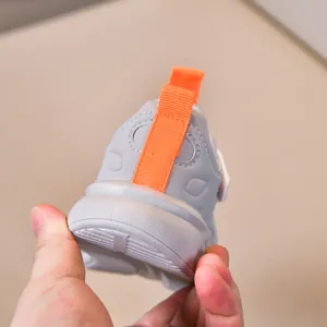 Detailed close-up of kids running shoes showing grey upper and orange heel pull tab