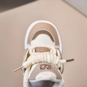 Λεπτομέρεια παιδικών sneaker με χοντρά μπεζ κορδόνια και ανάγλυφη δερμάτινη υφή