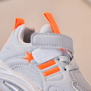 Macro detail of children's grey and orange sneaker featuring Velcro strap and mesh tongue