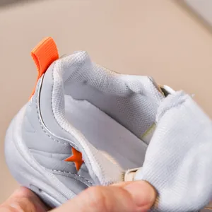 Detail view of children sports shoes featuring orange heel tab and star decoration