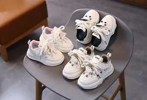 Dettaglio di scarpe da ginnastica in pelle per bambini con simpatiche bambole 3D sui lacci