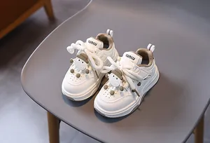 Dettaglio di scarpe da ginnastica per bambini color crema con pecora 3D e lacci in cotone