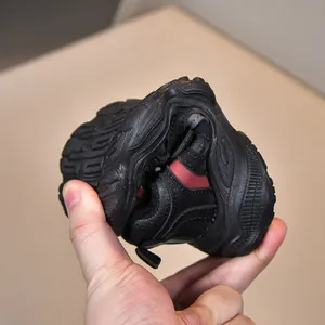 Baskets noires pour enfants avec détails rouges montrant la semelle souple et adhérente