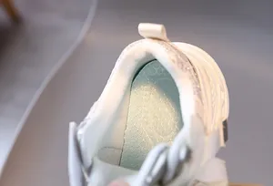 Close-up of soft padded lining and non-slip blue insole of the white mesh kids' sneaker