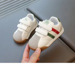 Detail of kids white sneakers with red-green stripes and non-slip rubber soles