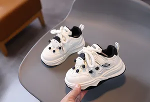 Dettaglio di sneaker bianche per bambini con cuori neri e ciondolo a forma di agnello
