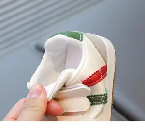 Detail of children's white leather sneakers with red-green stripes and hook-and-loop straps