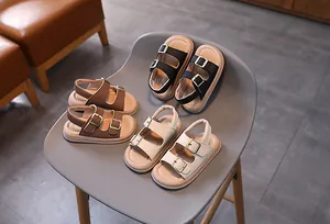 Three pairs of open-toe children's sandals in black, brown, and beige with metal buckles