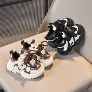 Zapatillas transpirables para niños en marrón y negro sobre un sofá minimalista