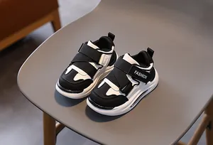Nahaufnahme von schwarz-weißen Leder-Kinderschuhen mit Klettverschluss und weicher Sohle