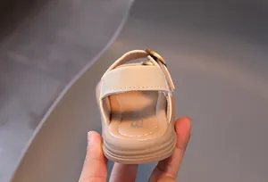 Detail of toddler beige sandal featuring adjustable velcro strap and premium metal buckle
