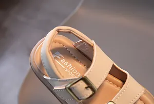Detailed macro shot of beige kids sandals showing metal buckle and fine stitching