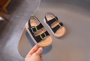 Detailed close-up of kids beach sandals with adjustable black straps and gold buckles
