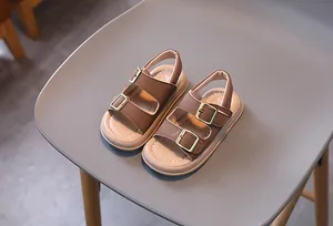 Detail of children's brown leather sandals with adjustable gold buckles and soft rubber soles