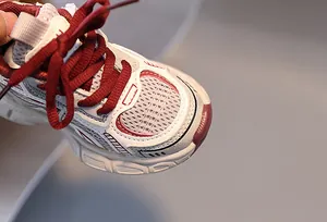 Gros plan sur baskets enfant en maille respirante avec lacets bordeaux et cuir blanc