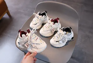 Detail view of breathable mesh kids sneakers with hook-and-loop straps on a chair