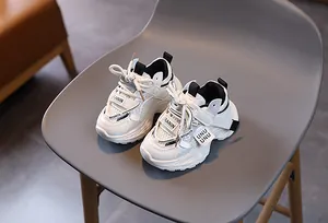 Detail view of boys' white mesh sports sneakers with anti-slip sole and strap detail