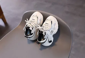 Detail of white mesh kids sneakers with thick soles and stylish branding accents