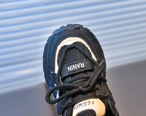 Close-up of breathable mesh and leather details on kids' black and white chunky sneakers