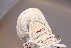Macro view of white kids sneakers showing breathable mesh and red RANIN tongue label