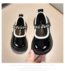 Nahaufnahme von Mädchen-Mary-Janes aus schwarzem Lackleder mit Strasssteinen und Gummisohle