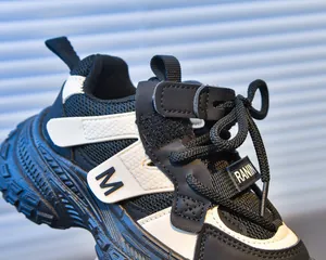 Detail of kids chunky sneakers featuring mesh fabric, M logo, and velcro strap closure