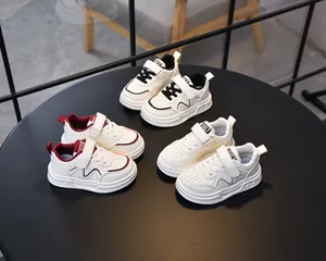 Overhead view of kids leather sneakers in three colors with velcro straps on round stand