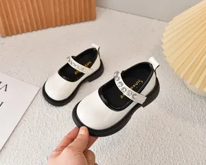 Detalle de zapatos Mary Jane blancos para niña con correa de strass y suela negra gruesa